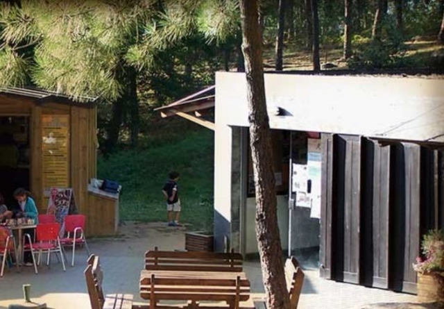 mesas de madera para comer con un edificio blanco de fondo